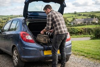 Homme en flanelle déballant un équipement photo en campagne